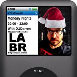 Promotional artwork for my radio show. It's designed to look like the now playing screen on a classic iPod, with the show info on the right side of the screen, and a photo of me on the left. In this festive version of the artwork, I am wearing a Santa hat. It details that the show is broadcast on Mondays from 7pm until 9pm UK time.