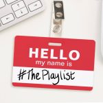 The artwork for this week's radio show. It features a generic workplace nametag laying on a desk. On it is writtern "Hello, my name is #ThePlaylist"